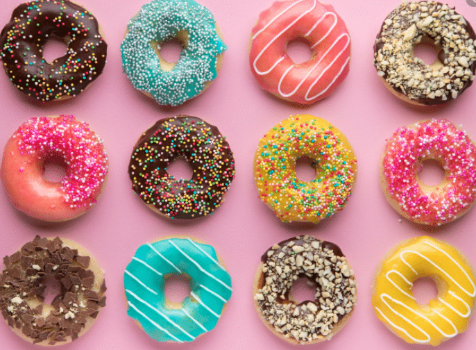 Apartments For Rent in Katy TX, Oak Park Apartments Colorful donuts are arranged on a pink background at Oak Park Apartments.